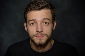 Portrait of an attractive young man with a beard on a dark background.