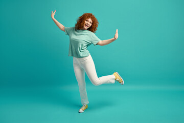 Obraz premium Full-length portrait of amazing positive young red-haired teenage woman with freckles shiny face wearing casual youth clothes and laughing dancing isolated on green studio copy space background
