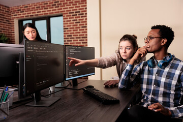 Software developer asking coder for help with html code, pointing at database script on terminal...