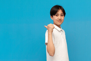 asian boy of twelve years old in white t-shirt shows back on blue isolated background