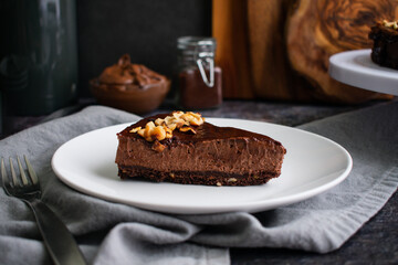 Slice of Chocolate Hazelnut Mousse Cake on a Plate: Dark chocolate and hazelnut mousse pie on a white plate with a fork