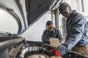 Fototapeta na wymiar Two men mechanics completing car engine diagnostics with laptop in a repair shop. High quality photo