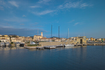 Fototapeta na wymiar Panorama of the city of San Vincenzo, seen from the sea, with the marina and the church. Blue sky and clouds. Livorno, Tuscany, Italy