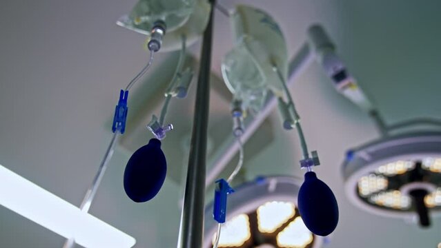 Plastic bags filled with medicines hanging from the drop counter stand. Tubes and enema pears. Low angle view.