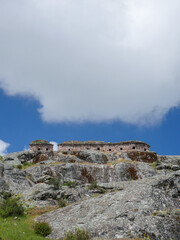 Marcahuasi chullpas, house made with stones on the top of a rocky mountain, archaeological remains in the mountains with a background of blue sky with cumulo clouds in South America