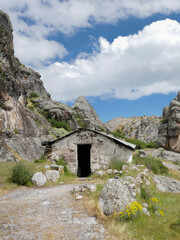 Fototapeta na wymiar old hut in the middle of a rocky mountain with blue sky and clouds in South America