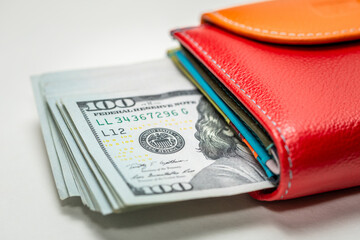 A pile of new design 100 US dollar bills in a colored wallet, on a white background. Cash banknotes of 100 dollars. The concept of wealth, business, finance, bank, currency, economy