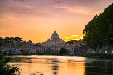 Fototapeta premium St. Peter's basilica across Tiber River canal at sunset in Rome, Italy