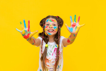 A cute little schoolgirl with stained hands in paint, A child is engaged in drawing, a girl has stained her hands in paint, A girl shows her hands that she has stained in paint.