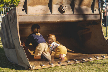 Children climbing inside excavator scoop