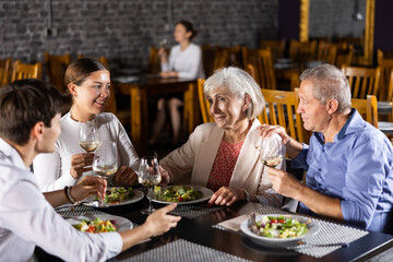 Fototapeta na wymiar Elderly couple and young couple chatting and enjoying dinner in restaurant