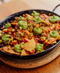 Plato de nachos con carne, queso y guacamole