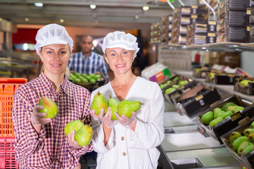 Fototapeta Happy emotional female workers of food factory warehouse with ripe pears in hands obraz