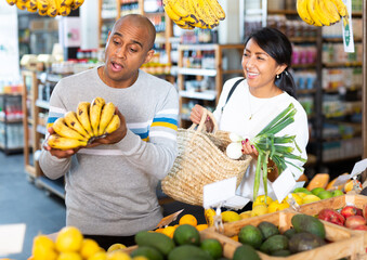 Fototapeta Man and woman picking ripe bananas together at grocery supermarket obraz