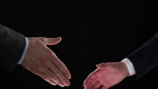 The men shake hands. Shaking hands after making a profit on a black background