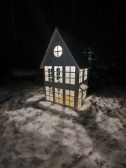 Dollhouse with light from windows on a winter street - 610467149