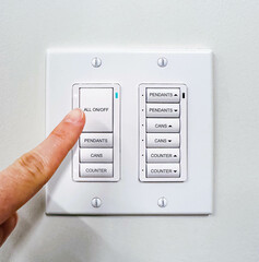 A finger press on-off button on a modern intelligent light control mounted on a white wall in a meeting room. A minimal design of energy saving, electricity power, and lifestyle concepts. 