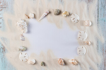 Obraz na płótnie Canvas Card, sand and seashells on blue vintge wooden planks, frame for summer advertisement 