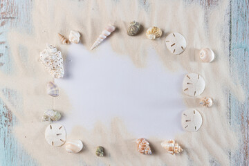 Card, sand and seashells on blue vintge wooden planks, frame for summer advertisement	