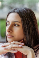 Portrait of pensive Indian woman looking away waiting someone on the street while sitting at the cafe. People lifestyle concept 