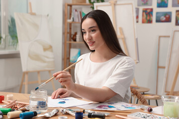 Fototapeta premium Beautiful young woman painting in studio. Creative hobby