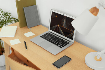 Naklejka premium Cozy workspace with laptop, smartphone and lamp on wooden desk at home