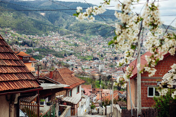 Obraz premium Urban panoramic view of the European city with tiled roofs and narrow streets located on the hills. The Balkan city of Sarajevo, the capital of Bosnia and Herzegovina
