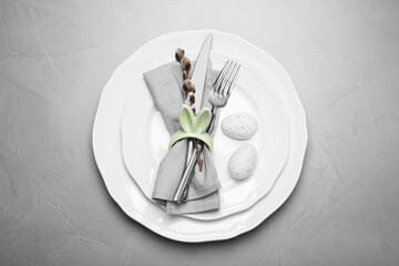 Festive table setting with painted eggs and willow twig on light grey background, top view. Easter celebration