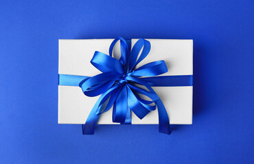 Beautiful gift box with bow on blue background, top view