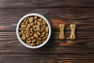 Dry dog food and treats (chew bones) on wooden floor, flat lay