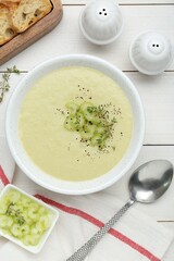 Bowl of delicious celery soup served on white wooden table, flat lay