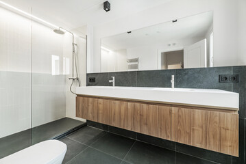 Fototapeta na wymiar Contemporary designer bathroom with large frameless mirror, green marble on the wall