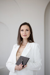 Fashion and beauty, stylish makeup artist in a white jacket with makeup brushes in her hands, business portrait of a makeup artist stylist or director of a beauty studio, modern light room,