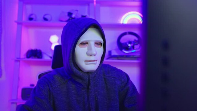 Short of computer hacker wearing white mask stealing data from a laptop. 