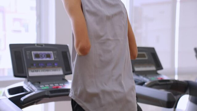 Asian young amputee without arm run on treadmill machine in fitness.