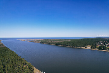 Aerial view drone of river goes into the sea. Delta of Vistula river goes in Baltic Sea in Sobieszewo Gdansk Poland. Forest and small village around river