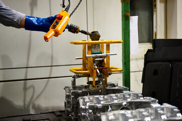 Warehouse of an automobile plant, a worker lifts the cylinder block of an internal combustion engine with a special grip