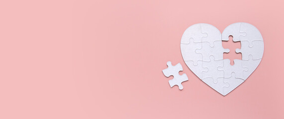 White puzzle heart with missing piece outside. Copy space.