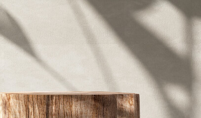 Natural log wood podium table in sunlight, tropical banana tree shadow on beige concrete wall for...