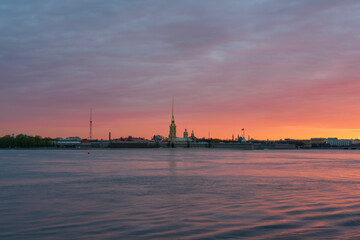 Fototapeta na wymiar View of the Peter and Paul Fortress and the Neva River against a pink dawn sky with clouds on a sunny spring morning, St. Petersburg, Russia