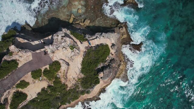 Top down drone lifting shot of waves rooling at Punta Sur on a sunny day.