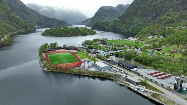 Soccer field and residential area close to Matrefjord in town of Matre in western Norway - Rising aerial
