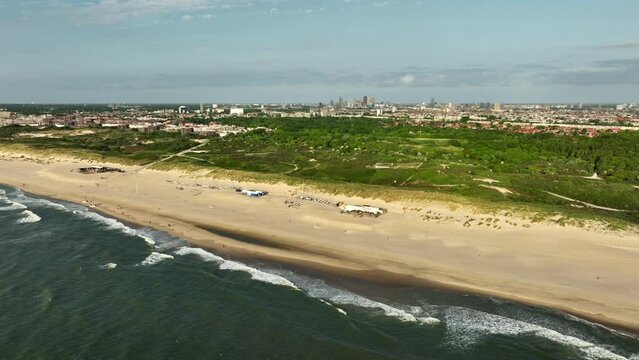 Aerial view of green dune and sandy beach with Den Haag city in background, Netherlands 