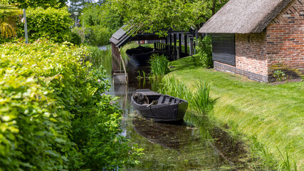 Small black wooden boat in the canal at Giethoorn, Netherlands.