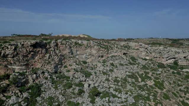 Aerial drone forward moving shot over steep rocky cliffs called Dingli Cliffs in Rabat, Malta on a sunny day. Sea and rock formations.