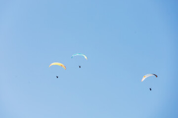 Paragliders flying in the sky with colorful paraglides 