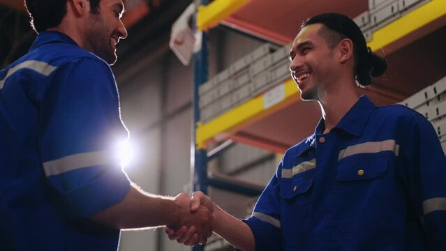 Two smart engineer worker in uniform safety wear helmet congraturation of job successful shaking hands with together in manufacturing plant. Industry and Warehouse concept