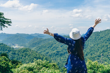 Woman feeling or admiring nature fresh air by stretching arms during meadows and mountains - concept of refreshment, active healthy lifestyle and holidays.