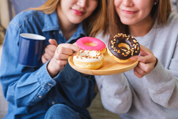 Closeup image of a young couple women holding and eating donuts together