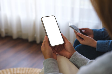 Mockup image of a couple woman holding and using a white mobile phone with blank desktop screen together